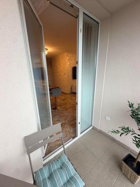 Open balcony door to a 3-room apartment with a comfortable armchair and flooring.