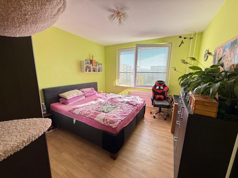 Bedroom in a 2-room apartment with wood-patterned flooring and a comfortable bed.