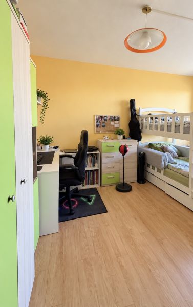 Children's room in a two-room apartment with a bed, a desk, and a floor with a wooden decor.