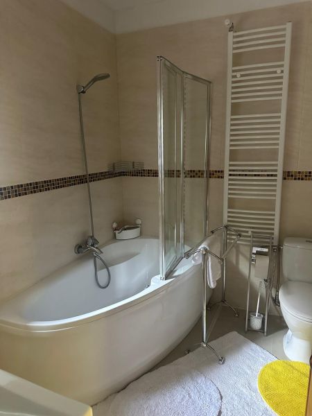 A bathroom with a bathtub, a white ladder, and tiles in a 3-room apartment.