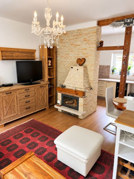 Living room with a fireplace, wood-patterned floor, carpet, chandelier, and wooden furniture.