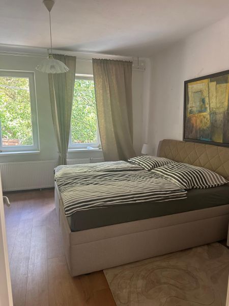 Bedroom in a 3-room apartment with a bed, wooden decor flooring, and a picture on the wall.