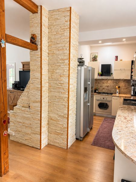 A kitchen in a 3-room apartment with a stone wall and a wooden decor floor.