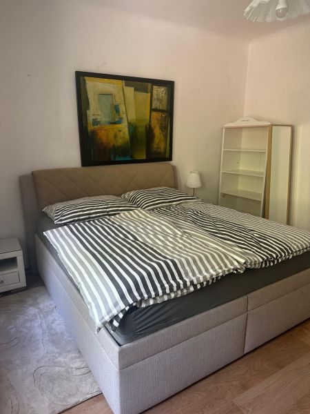 Bedroom in a 3-room apartment with a picture above the bed, a shelf, and a floor with a wooden decor.