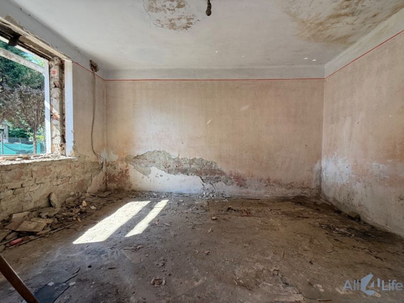 Abandoned room with damaged walls and a window in a family house.