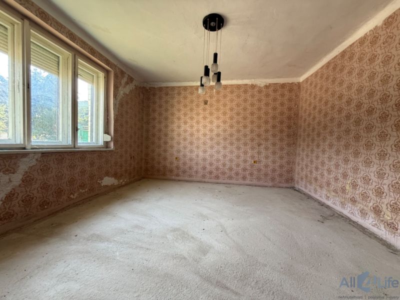 A room in a family house with floral wallpaper and large windows.
