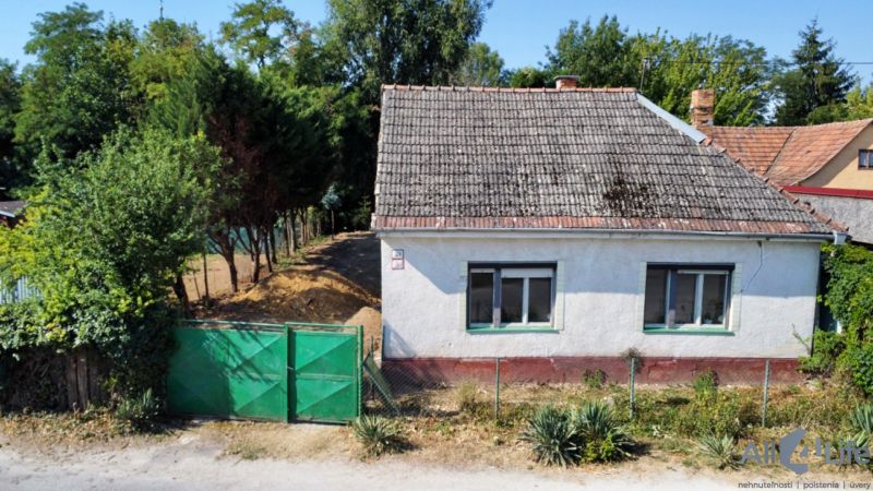 A family house on St. Florian Square in Krakovany, surrounded by greenery and a fence.
