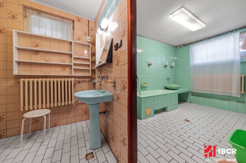 Bathroom in a family house with green tiles and a blue sink, retro design.