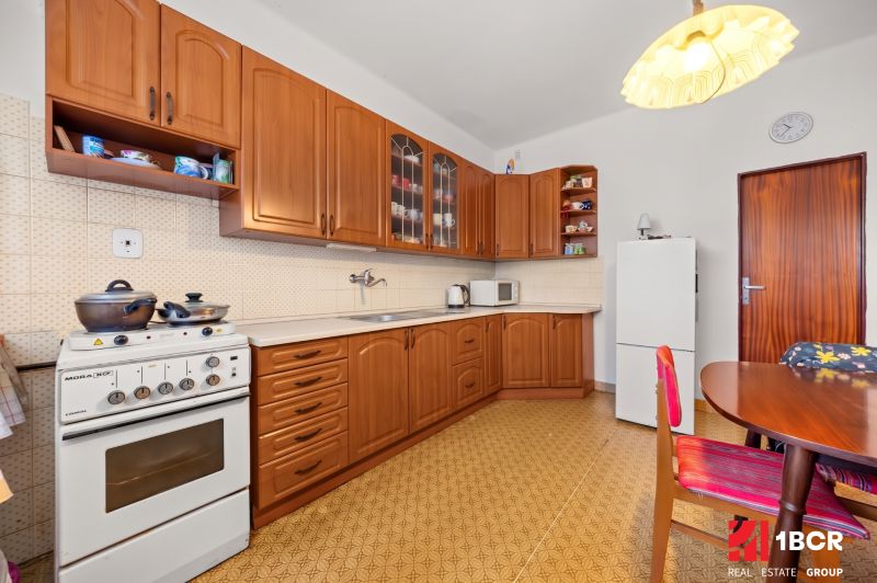 A kitchen in a family house with wooden cabinets, a stove, and a dining table.
