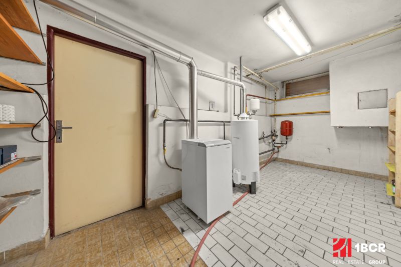 Boiler room with equipment and shelves in a family house, with piping on the tiles.