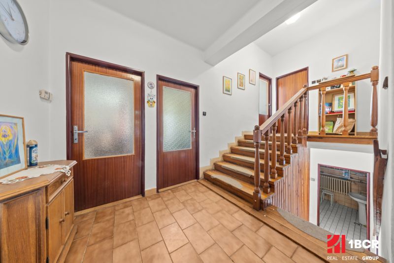 A hallway of a family house with wooden railing and wall decorations.