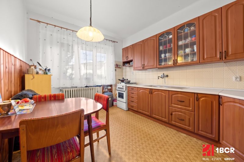 A kitchen in a family house with wooden decor furniture and curtains on the windows.