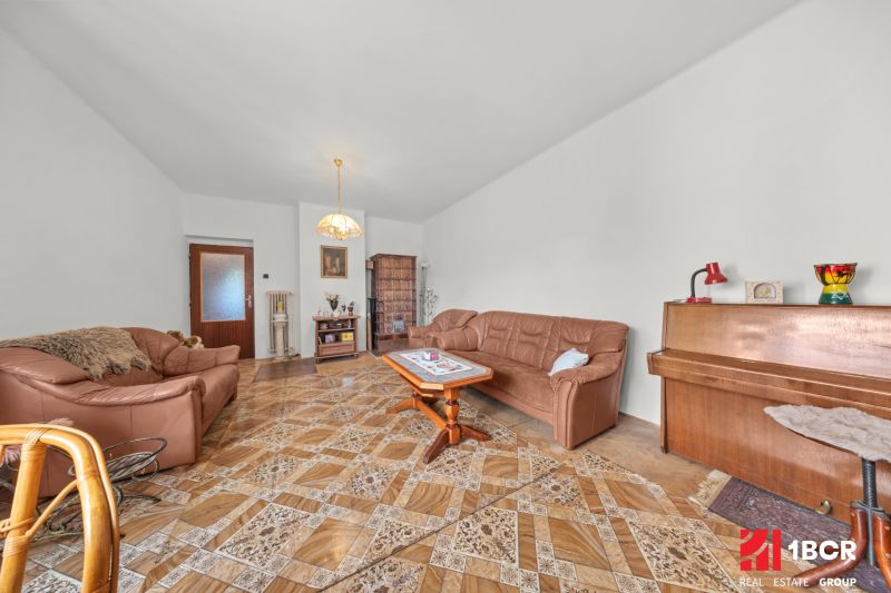 Living room in a family house with a leather sofa, piano, and wooden decor flooring.