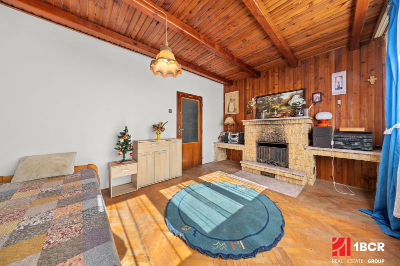 Interior of a family house with a fireplace, wooden decor flooring, and a carpet.
