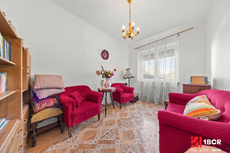 Living room in a family house with red armchairs and a table on a floor with a wooden decor.