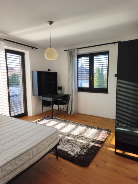 Bedroom in a family house with wood-patterned flooring, a desk, and a carpet.