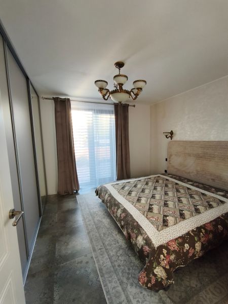 A bedroom in a family house with a large bed, cabinets, and an elegant chandelier.