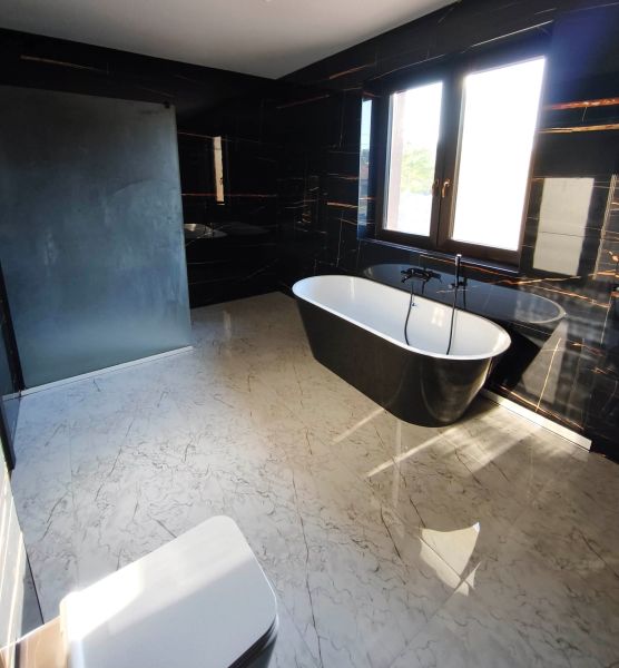Elegant bathroom with a freestanding bathtub and black walls in a family house.