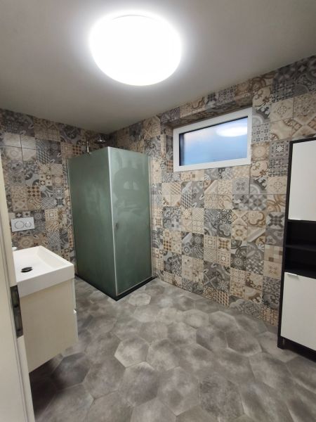 A bathroom in a family house with patterned tiles and a shower corner.