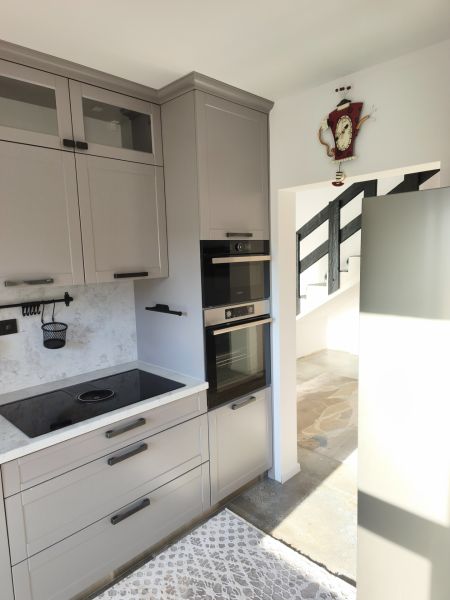 A kitchen in a family house with a built-in oven, grey cabinets, and an induction cooktop.