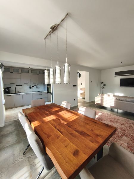 A solid wood dining table in a family house with a kitchen and living room on a floor with a wooden decor.