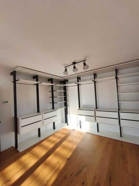 A wardrobe in a family house with shelves, drawers, and a wooden decor floor.
