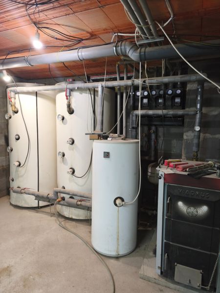 Technical equipment in a family house with a boiler and a furnace, pipes across the room.