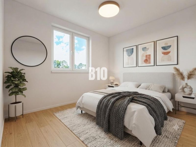 A bedroom with a bed, wood-patterned flooring, a plant, and a round mirror in a family house.