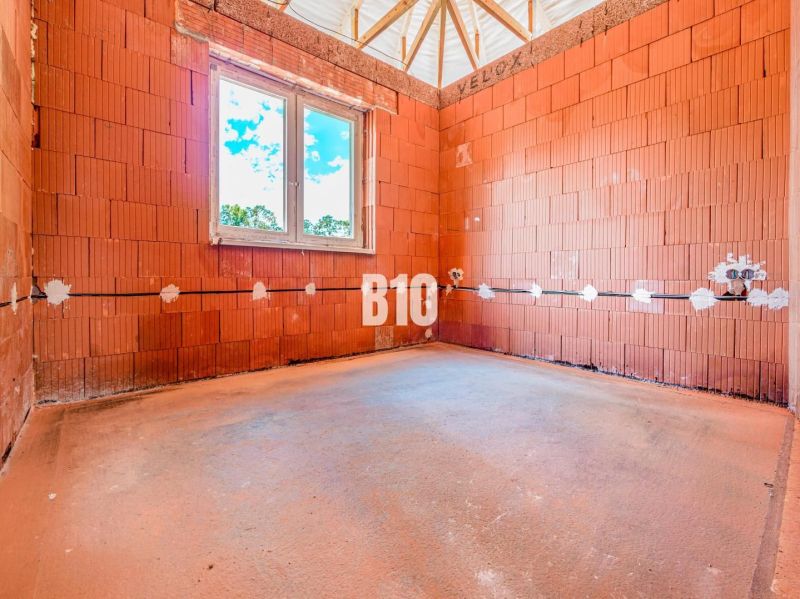Unplastered bricks and a window in a family house in Čeľadice.
