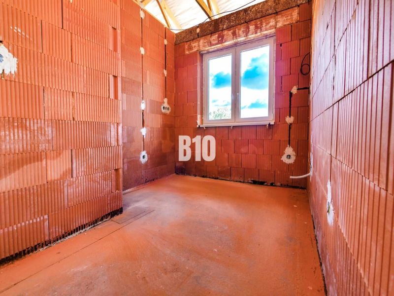 A newly built family house in Čeľadice with exposed brick walls and a plastic window.