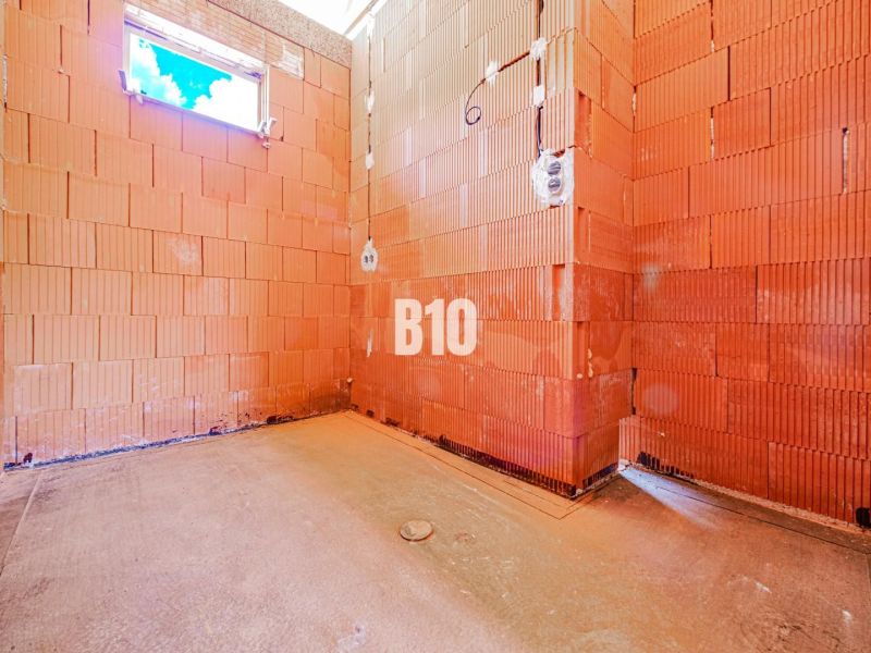 An unplastered room in a family house with red brick walls.
