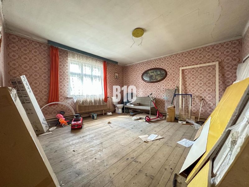 A room in a family house with retro wallpaper, a wooden decor floor, and toys.