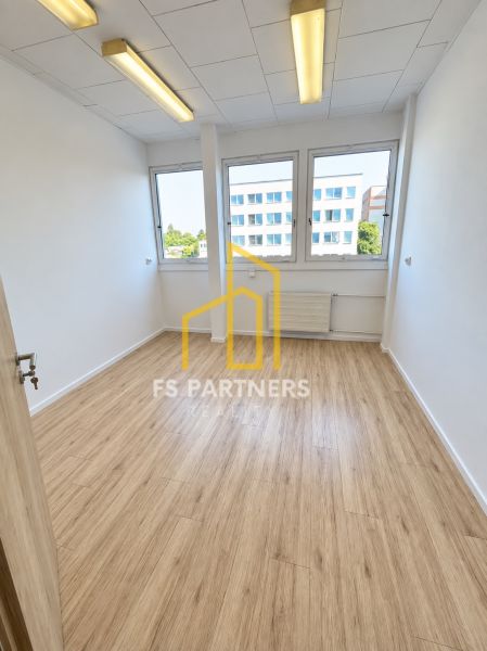 An office with a wooden floor design, interior with large windows and ceiling lighting.