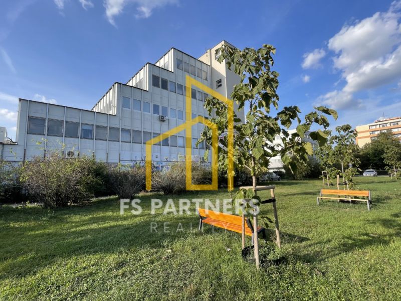 Offices on Záhradnícka Street in Komárno with benches and young trees.