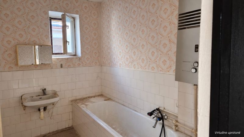 A bathroom in a family house with a bathtub, a sink, and a gas boiler.