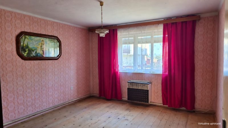 A room in a family house with pink wallpaper and a wooden decor floor.