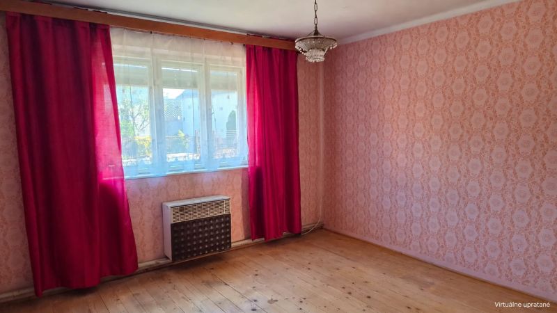 A room in a family house with wallpaper, red curtains, and a wooden decor floor.