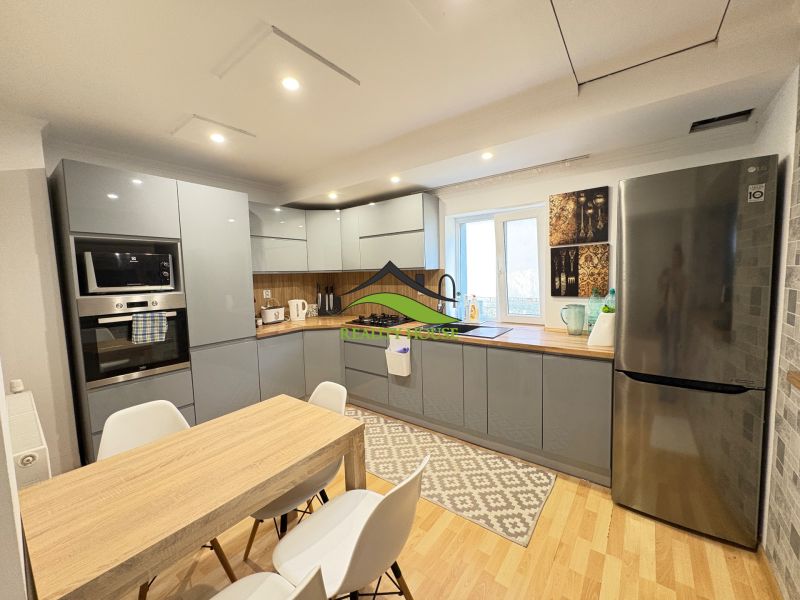 A kitchen with a wood-patterned floor, a dining table, and an elegant gray kitchen unit.