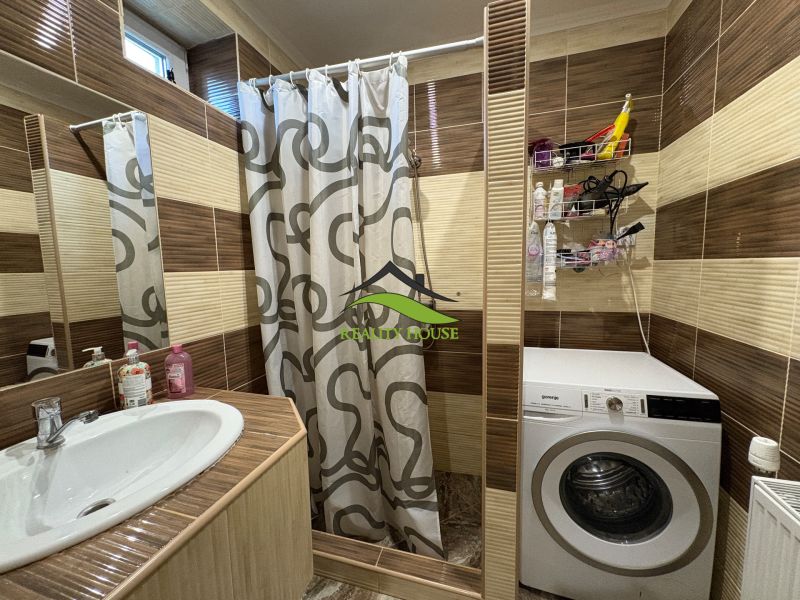 Bathroom in a family house with a sink, shower, and washing machine.