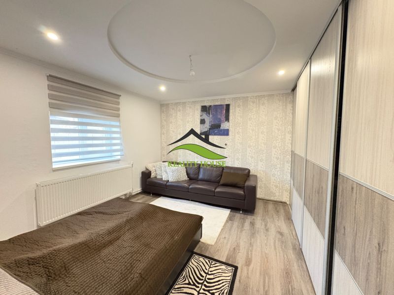 A room in a family house with a wooden decor floor, a sofa, and a bed.