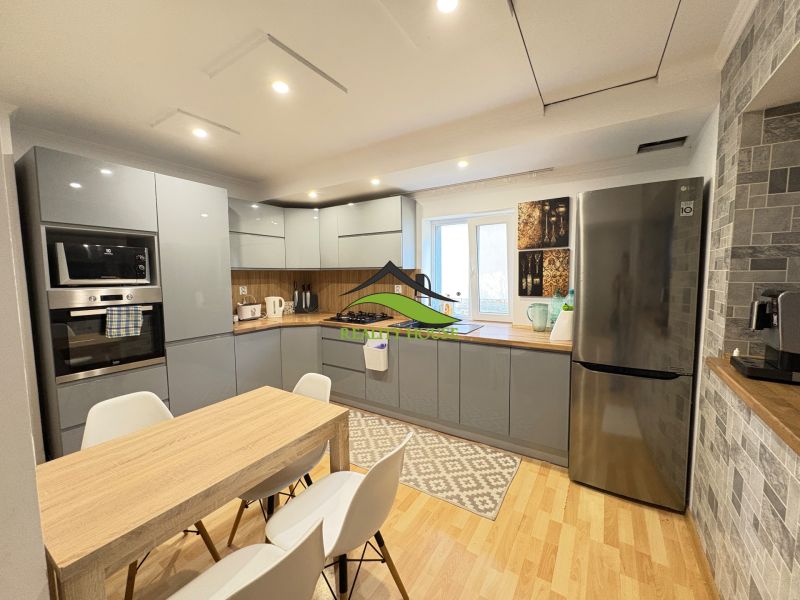 A kitchen in a family house with a wooden decor floor, white chairs, and appliances.