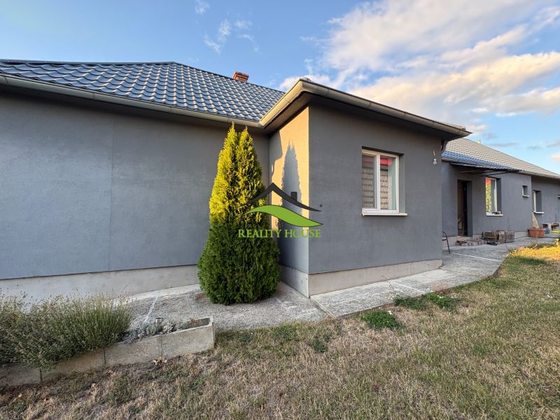A family house in Blatné Revištia with a manicured lawn and a wall in a gray shade.