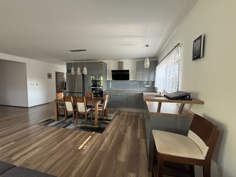 A kitchen in a family house with a wooden decor floor and a dining table.