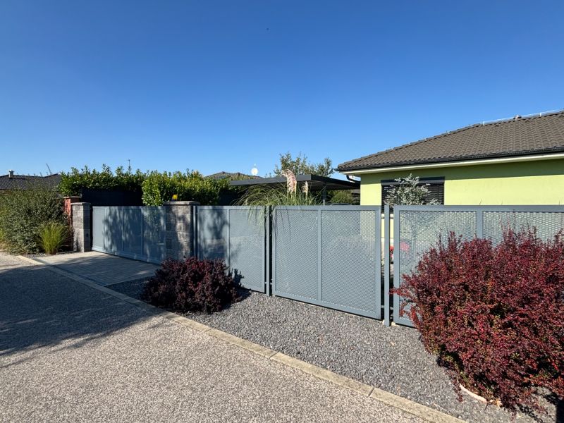 A family house on Figová Street in Bernolákovo with a metal fence and a landscaped garden.