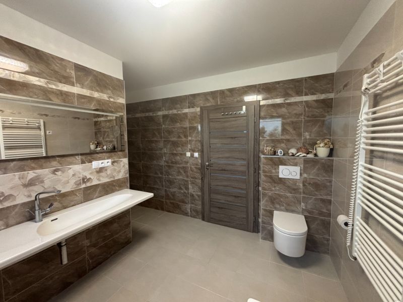 A bathroom in a family house with a large mirror and tiles with a marble pattern.