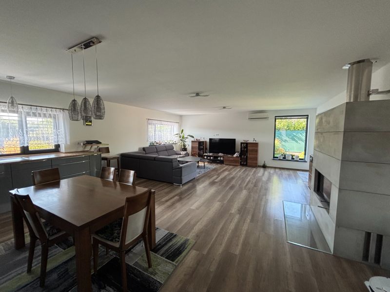 Living room in a family house with a wood-patterned floor, fireplace, and dining table.