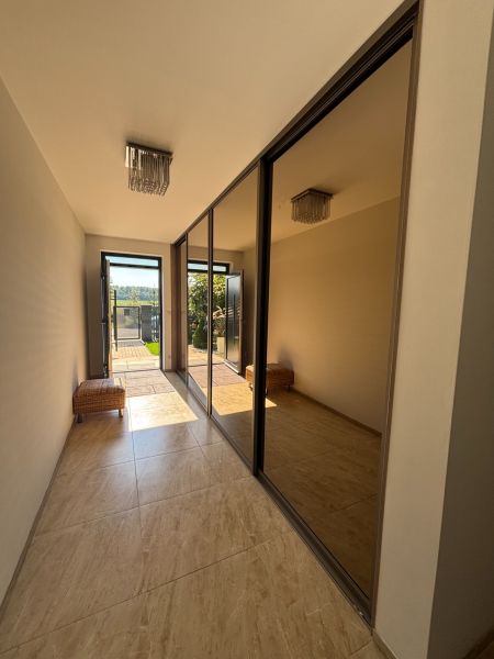 A hallway in a family house with a large mirror, tiles, and a chandelier.