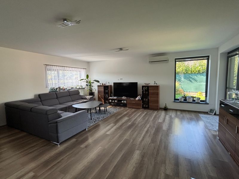 Living room in a family house with a dark sofa set and a floor with a wooden decor.