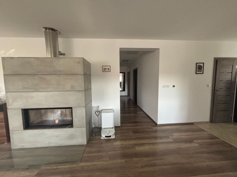 A fireplace in a family house with a wooden decor floor and light-colored walls.