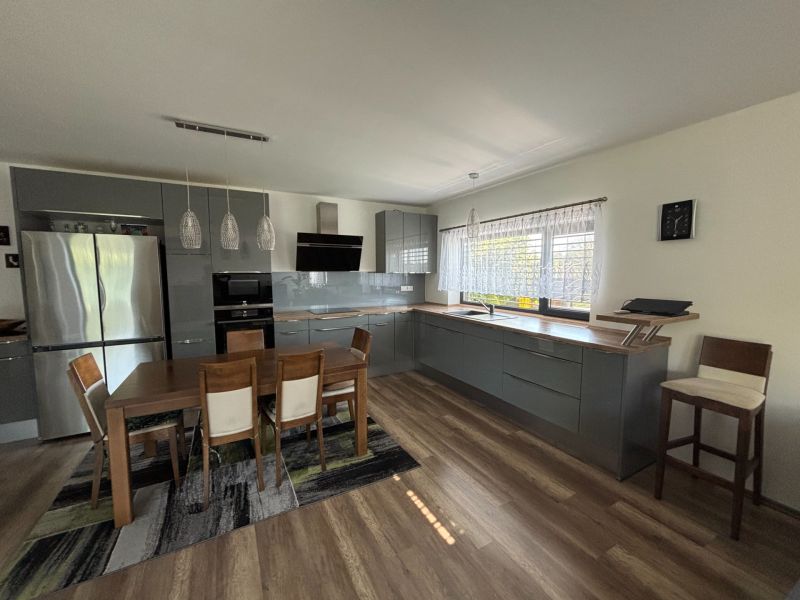 A kitchen in a family house with a wooden decor floor and a dining table.